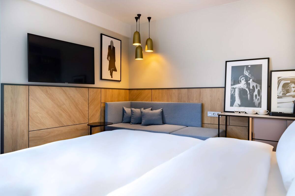 Une chambre d’hôtel moderne dotée d’un grand lit, d’un téléviseur à écran plat et d’un mur décoratif en bois.
