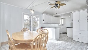 A modern kitchen with white cabinetry, a central island, and a dining area with wooden chairs.