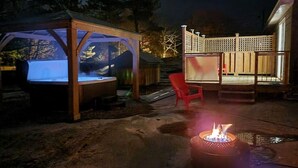 A hot tub area with a wooden deck and a fire pit.