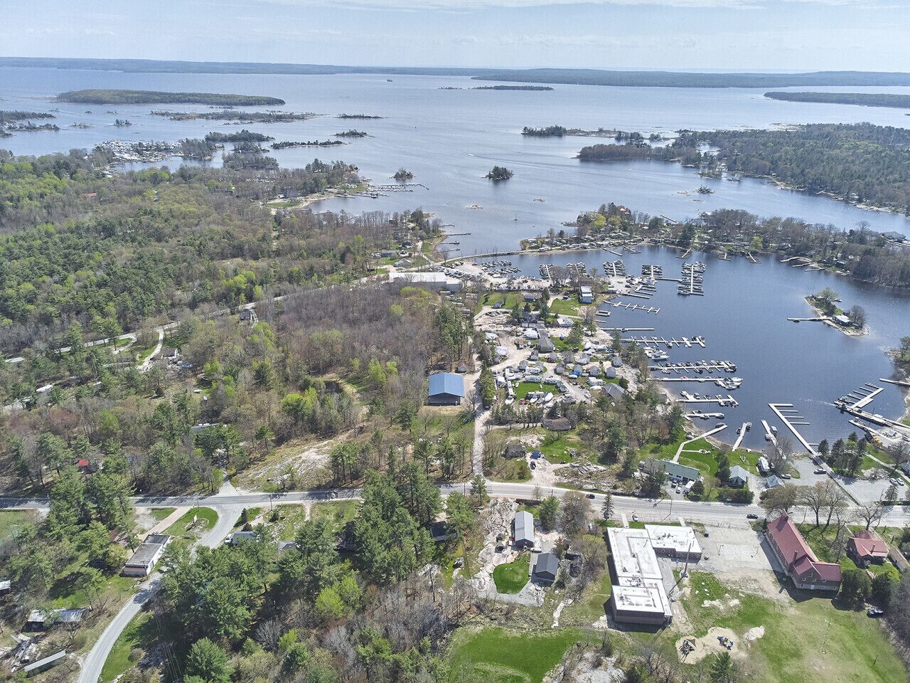 Vue aérienne d’une zone côtière avec un port de plaisance, des bateaux et des immeubles résidentiels.