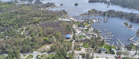 Vue aérienne d’une zone côtière avec un port de plaisance, des bateaux et des immeubles résidentiels.