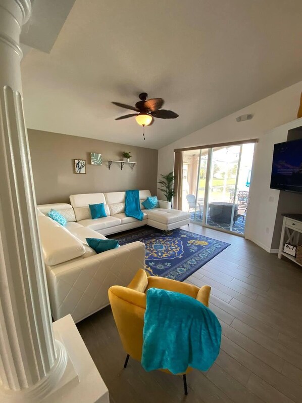 A spacious living room with a white sofa, a yellow armchair, and a ceiling fan.