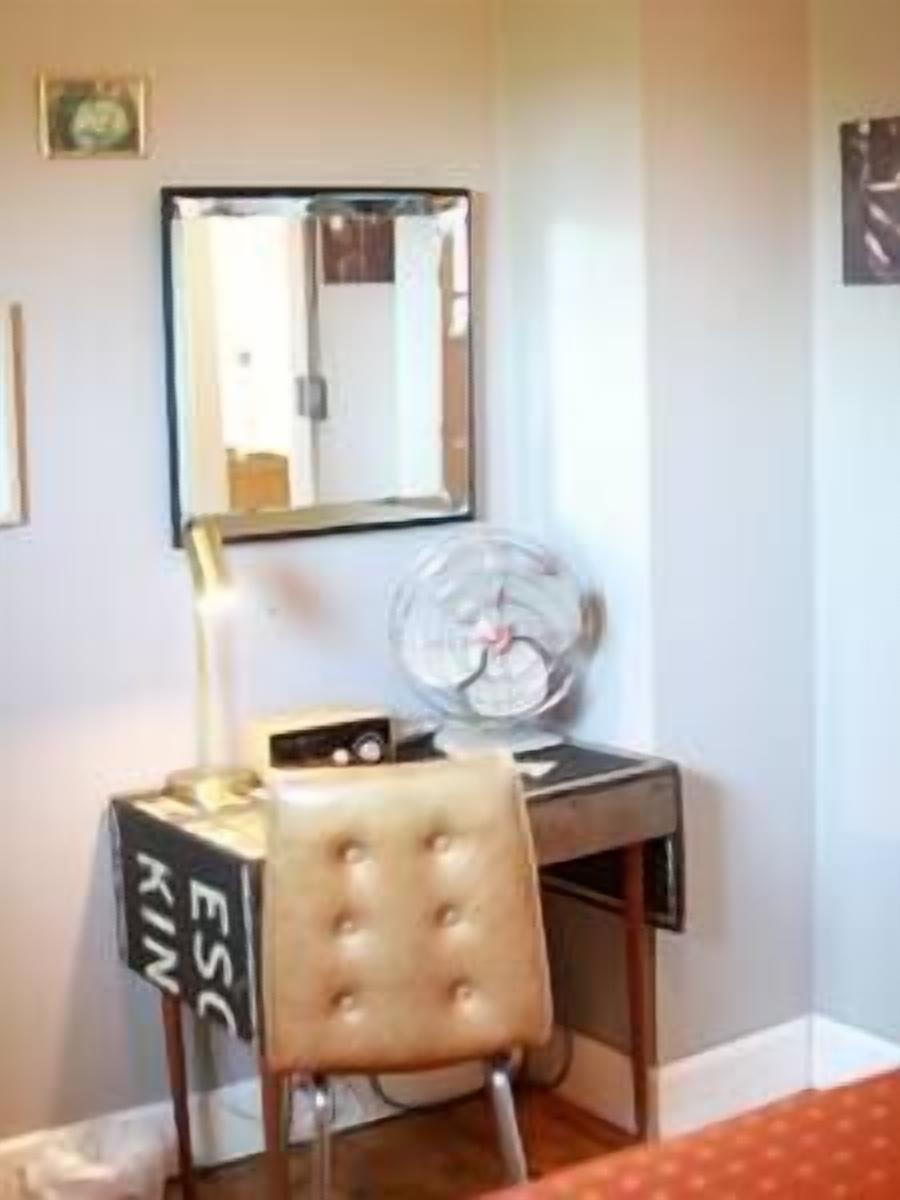A small office space with a desk, chair, lamp, and a mirror.