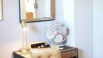 A small office space with a desk, chair, lamp, and a mirror.
