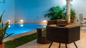 A poolside area with wicker furniture, a glass table, and a potted plant. - Beautiful home with private pool (Puerto Vallarta)