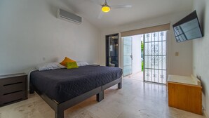 A bedroom with a bed, a nightstand, an air conditioning unit, a ceiling fan, and a sliding glass door leading to a balcony. - Beautiful home with private pool (Puerto Vallarta)