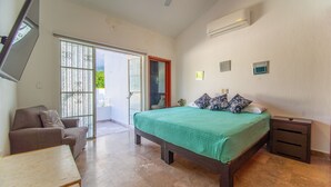 A bedroom with a bed, a chair, a nightstand, an air conditioner, and a sliding glass door leading to a balcony. - Beautiful home with pool (Puerto Vallarta)