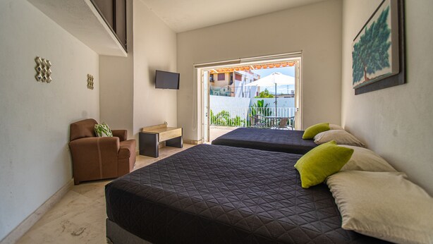 A hotel room with two beds, a desk, a chair, and a TV. - Beautiful home with pool (Puerto Vallarta)