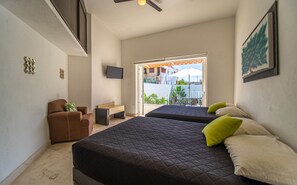 Une chambre d’hôtel avec deux lits, un bureau, une chaise et un téléviseur.