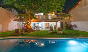 A poolside area with a dining setup, outdoor furniture, and a tree with lights. - Spacious home with private heated pool (Puerto Vallarta)