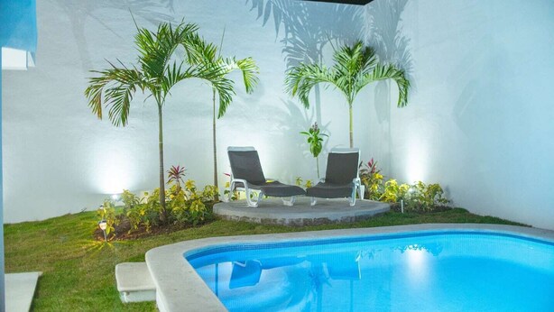 A swimming pool with two lounge chairs and two palm trees. - Spacious House with Private Pool (Puerto Vallarta)