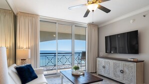 A hotel room with a balcony, a flat-screen TV, a white sofa, a coffee table, and a cabinet. - Azure 615 ~ 4BR Oceanfront Condo ~ Sleeps 10 ~ Spectacular Penthouse Views! (Fort Walton Beach)
