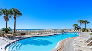 A swimming pool with lounge chairs and palm trees, surrounded by a paved deck. - Azure 615 ~ 4BR Oceanfront Condo ~ Sleeps 10 ~ Spectacular Penthouse Views! (Fort Walton Beach)