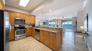 A modern kitchen with wooden cabinets, stainless steel appliances, and a large island. - Azure 615 ~ 4BR Oceanfront Condo ~ Sleeps 10 ~ Spectacular Penthouse Views! (Fort Walton Beach)