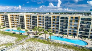 Ein mehrstöckiges Hotel mit Balkonen, einem Poolbereich und Blick auf den Strand.