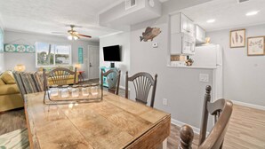 A dining area with a wooden table, chairs, and a ceiling fan. - Misty Harbor Townhome #15 (Panama City Beach)