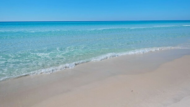 A beach with clear blue water and a sandy shore. - Misty Harbor Townhome #15 (Panama City Beach)
