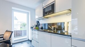 Een moderne keuken met een ingebouwde magnetron, roestvrijstalen apparatuur en een groot raam met uitzicht op een achtertuin.