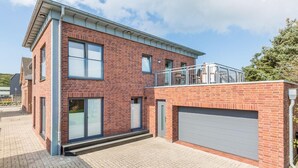 Een modern huis met twee verdiepingen, een bakstenen gevel, grote ramen en een garage.