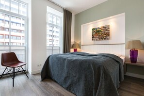 Un dormitorio moderno con una cama grande, una silla y una obra de arte en la pared.