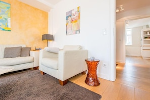 Una sala de estar moderna con un sofá, una mesa de centro, una lámpara y una mesa de cristal decorativa.