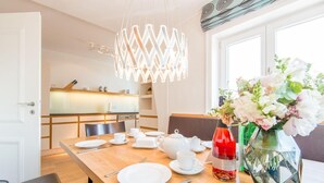 Un coin repas avec une table en bois dressée pour le repas, un luminaire décoratif au-dessus et un vase rempli de fleurs sur la table.