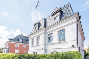 A two-story building with a white facade and a grey roof.