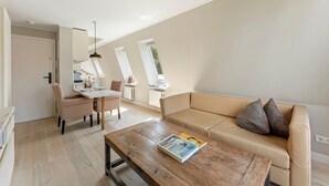 Una sala de estar moderna con una mesa de centro de madera, un sofá color beige y una zona de comedor con una mesa y sillas.