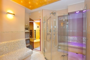Une salle de bain moderne dotée d’une douche à parois de verre, d’un banc et d’un meuble-lavabo avec un miroir.