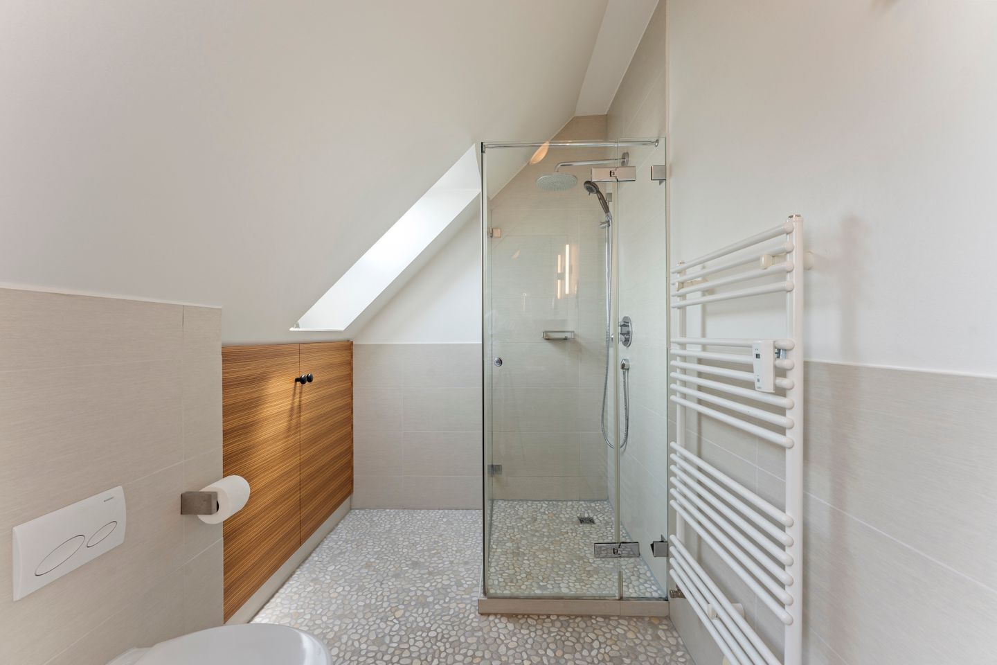Une salle de bain moderne avec une douche à parois de verre, un meuble-lavabo en bois, une baignoire blanche et un radiateur blanc.