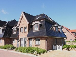 A modern two-story house with a brick facade, multiple windows, and a sloped roof.