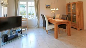 Un salon moderne avec un téléviseur à écran plat, une table à manger, des chaises et un meuble.