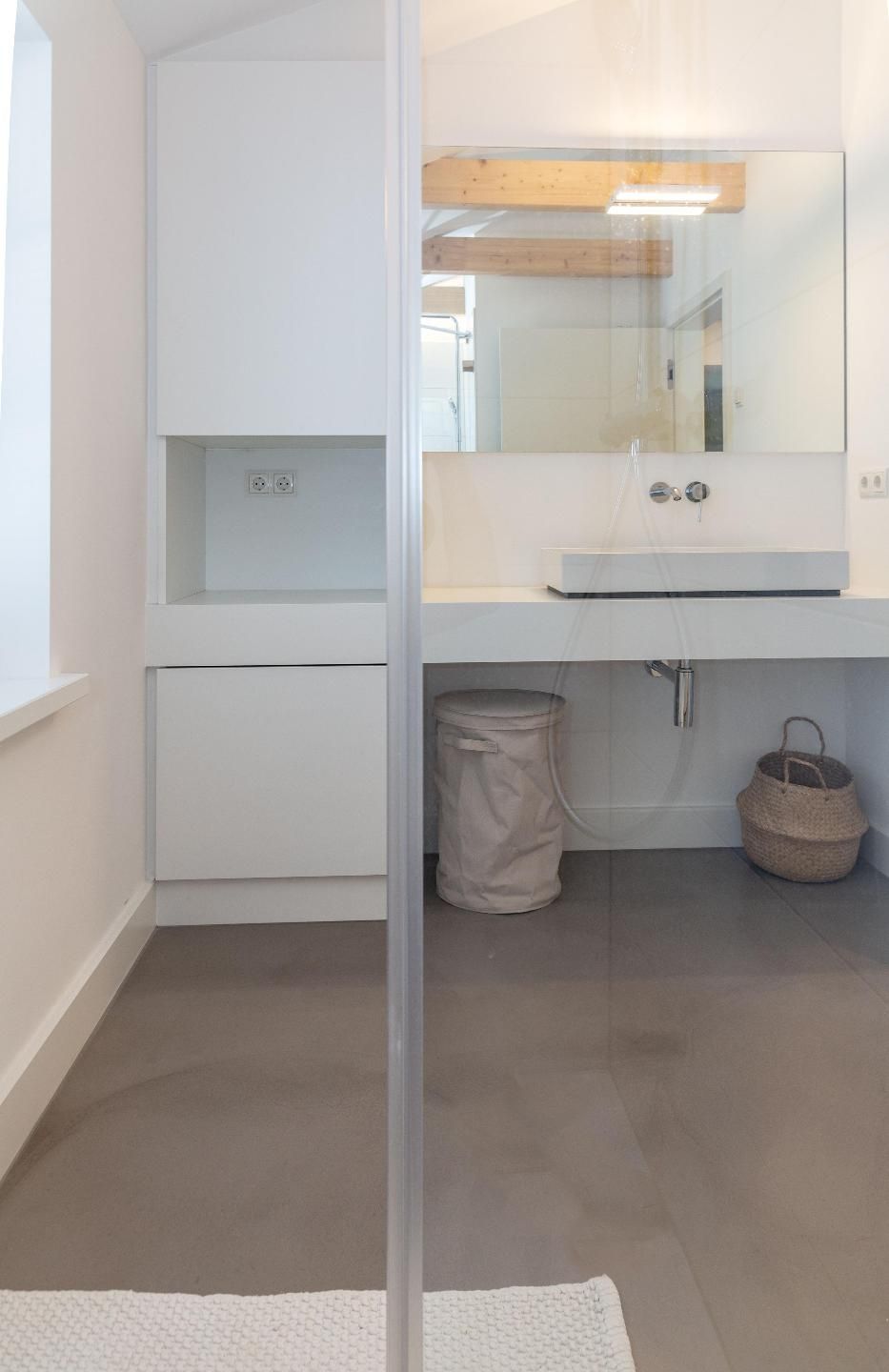 Een moderne badkamer met een witte wastafel, een grote spiegel en een douchecabine.