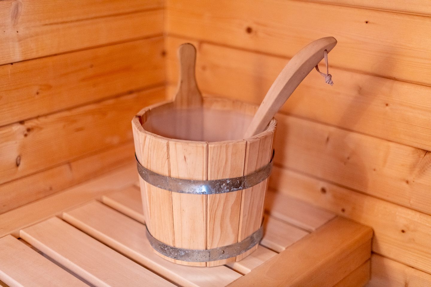 Eine Holzsauna mit einem Holz-Eimer und einem Holzlöffel.