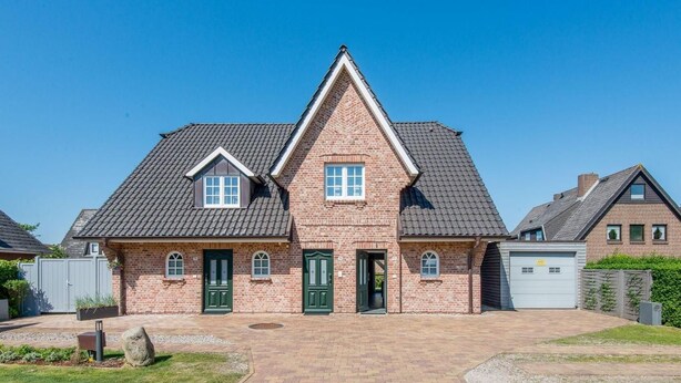 Une maison à deux étages avec une façade en briques, une entrée centrale et un garage.