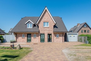 A two-story house with a brick facade, a central entrance, and a garage. - Haus Waldwinkel 18, Whg. Auszeit - Exklusiv. Strandnah. Auszeit. - Haus Waldwinkel 18, Whg (Sylt)