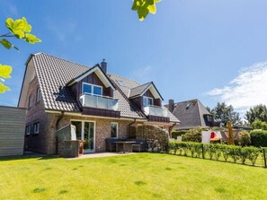 Ein zweistöckiges Haus mit einem geneigten Dach, einer Veranda und einem gepflegten Rasen.