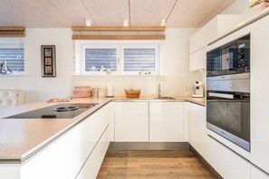 A modern kitchen with white cabinetry, a built-in oven, and a window above the sink.