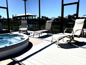 A poolside area with lounge chairs, a hot tub, and a view of the ocean and buildings. - Grand Oak Waterfront Resort - Pool Spa 2 King BR Kayaks Dock Arcade Pet-Friendly (Apollo Beach)