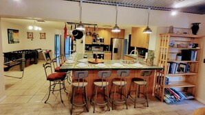 A spacious kitchen with a long island counter, bar stools, and modern appliances. - Grand Oak Resort Waterfront Pool/Spa/2 King BR/kayak/Pet extended stay discounts (Apollo Beach)