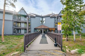 Un immeuble à plusieurs étages doté d’une terrasse en bois menant à l’entrée.