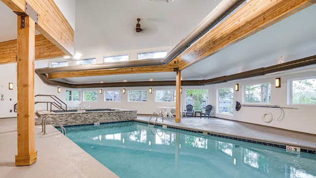 An indoor swimming pool with clear water, wooden beams, and a stone accent wall. - Silverthorne Condo: New Pool & Hot Tub + Fireplace (Silverthorne)