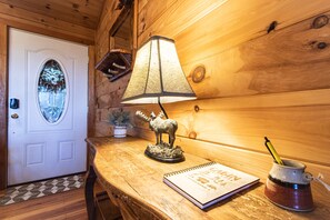A wooden interior with a door, a lamp, a moose figurine, a notebook, and a mug.