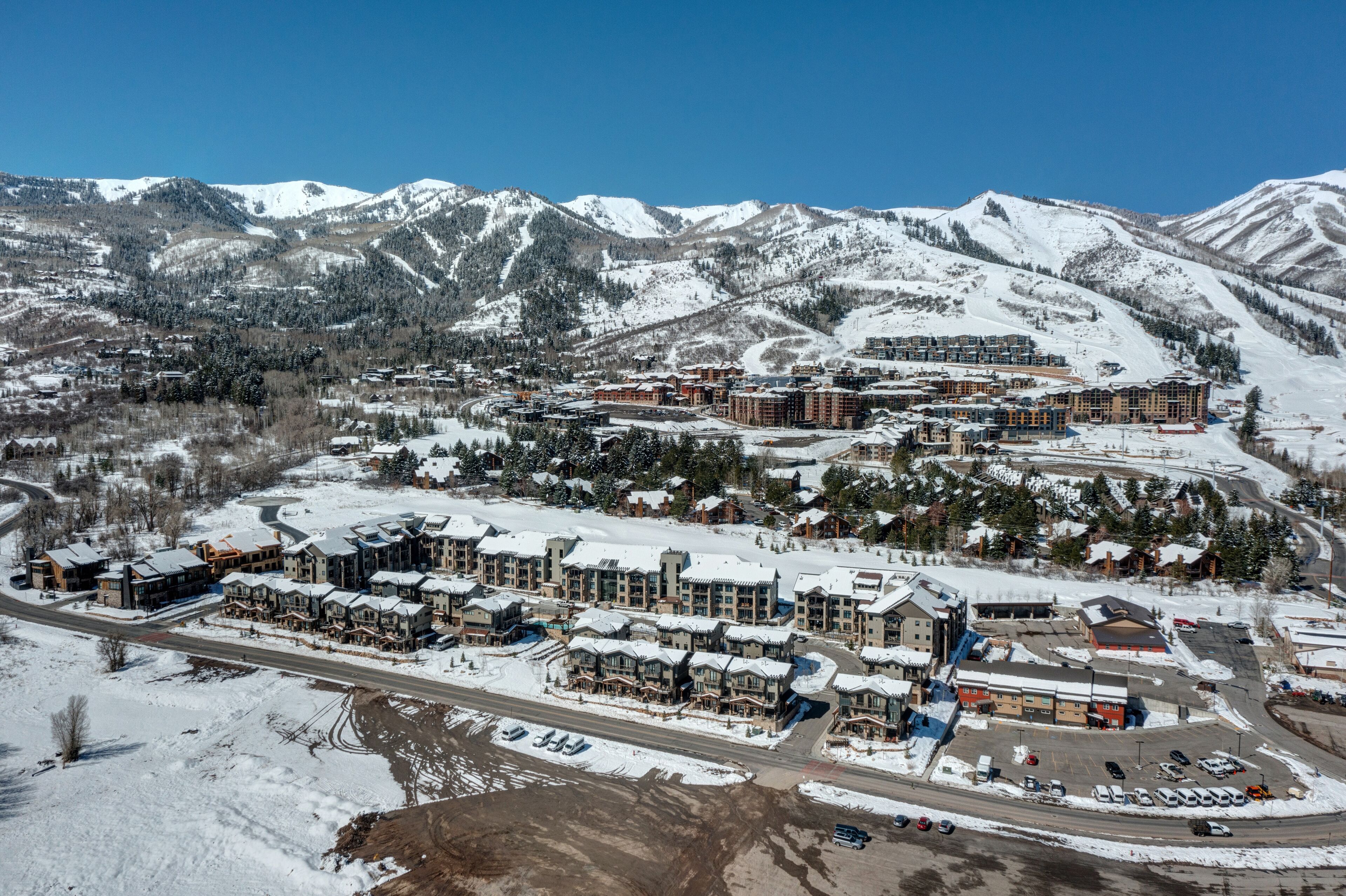 A resort with multiple buildings, a parking area, and a mountainous backdrop.