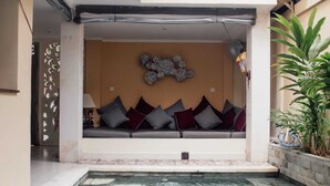 A modern indoor pool area with a seating area and a decorative wall. - Studio Bawa (Seminyak)