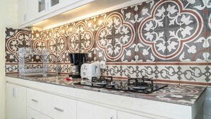 A kitchen with white cabinets, a gas stove, a coffee maker, and a toaster. - Studio Bawa (Seminyak)