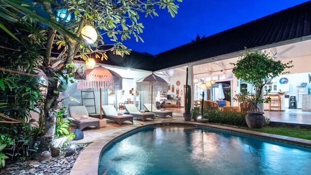 A pool area with lounge chairs and a covered seating area.