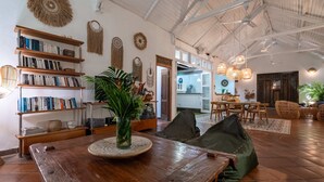 A spacious living area with a wooden table, bookshelves, and a dining area with chairs and a table.