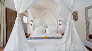 A bed with a canopy, two bedside lamps, and a decorative mirror on the wall.