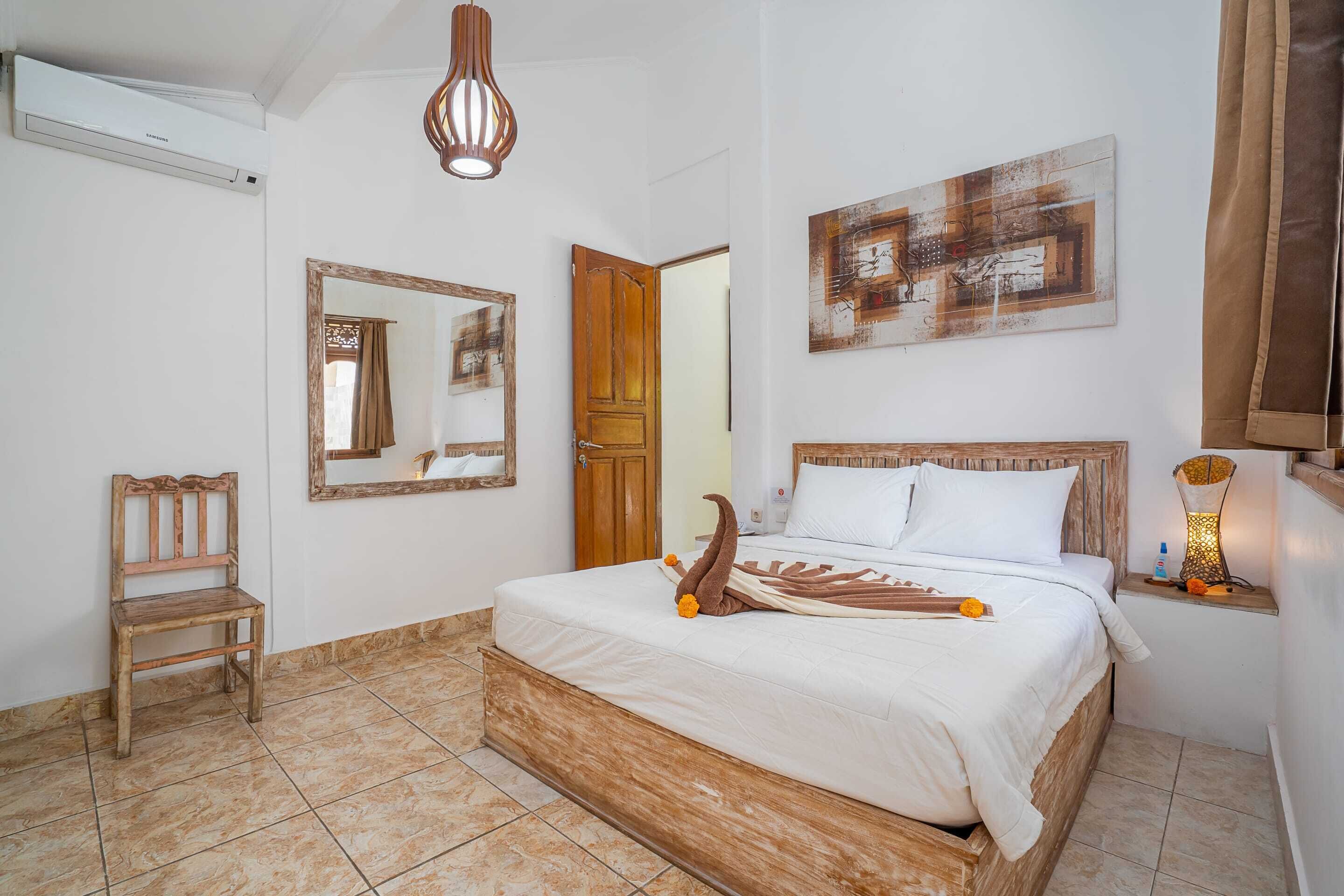 A bedroom with a wooden bed, a wooden chair, a mirror, and a painting on the wall.